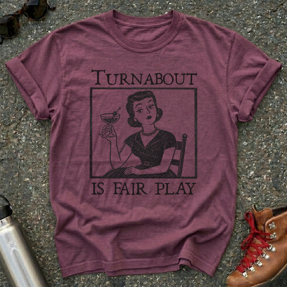 Comfort Colors t-shirt with a retro 1950s housewife holding a martini in vintage woodcut style and the words Turnabout Is Fair Play