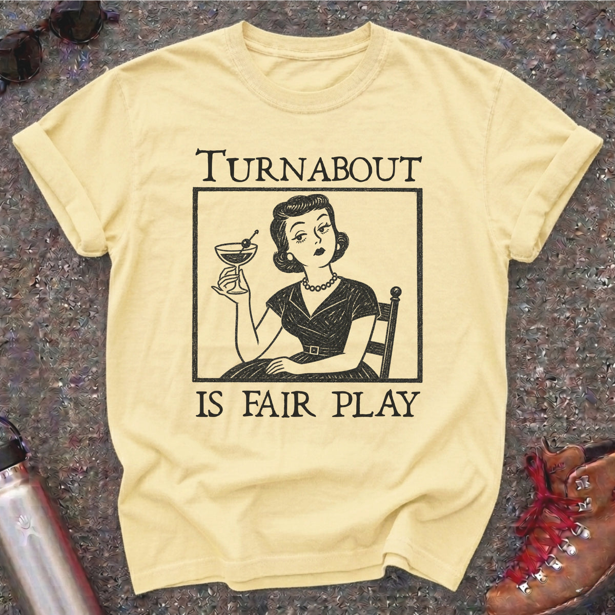 Comfort Colors t-shirt with a retro 1950s housewife holding a martini in vintage woodcut style and the words Turnabout Is Fair Play