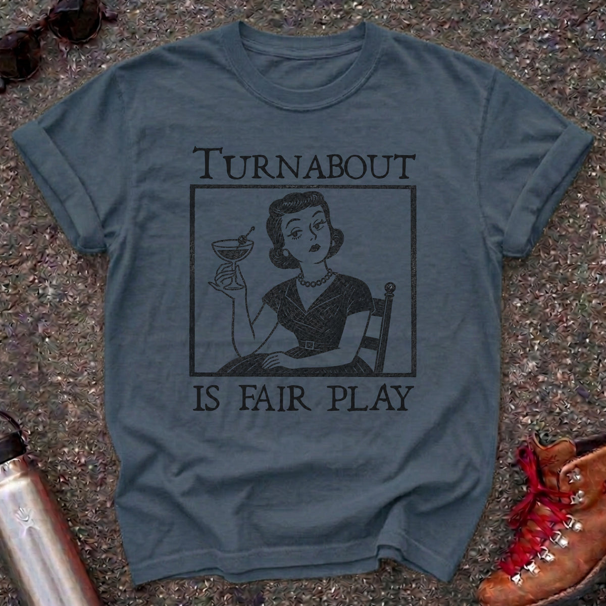Comfort Colors t-shirt with a retro 1950s housewife holding a martini in vintage woodcut style and the words Turnabout Is Fair Play