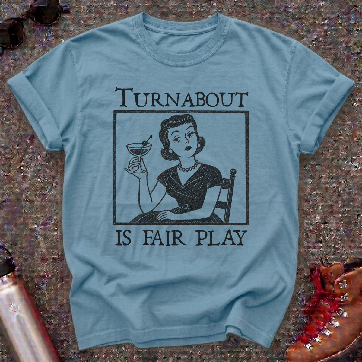 Comfort Colors t-shirt with a retro 1950s housewife holding a martini in vintage woodcut style and the words Turnabout Is Fair Play