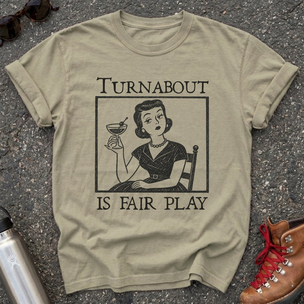 Comfort Colors t-shirt with a retro 1950s housewife holding a martini in vintage woodcut style and the words Turnabout Is Fair Play