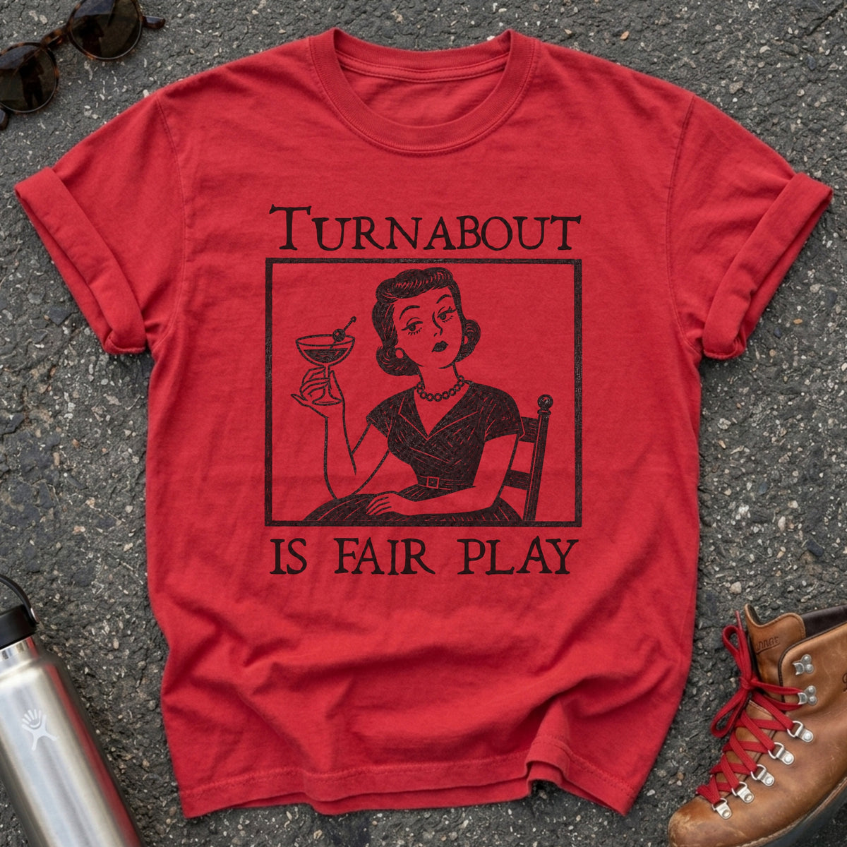 Comfort Colors t-shirt with a retro 1950s housewife holding a martini in vintage woodcut style and the words Turnabout Is Fair Play