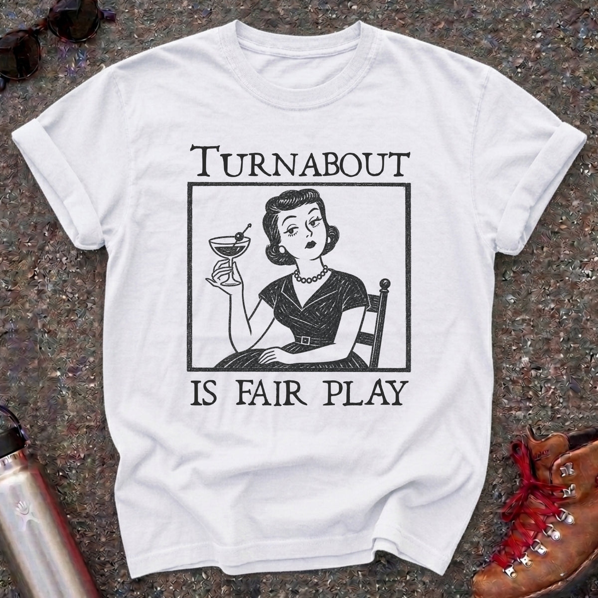 Comfort Colors t-shirt with a retro 1950s housewife holding a martini in vintage woodcut style and the words Turnabout Is Fair Play